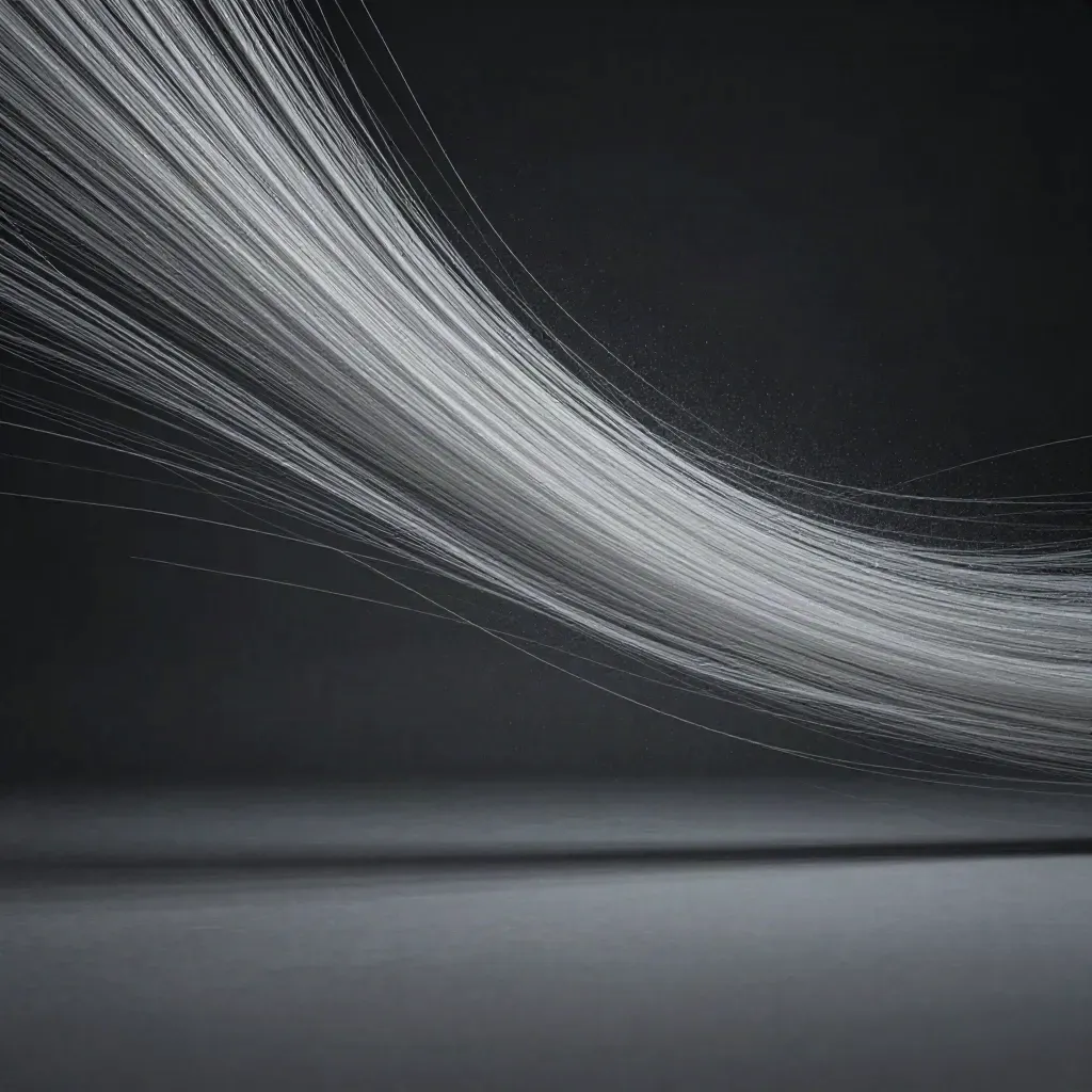Silver filaments converge into a soft white bloom in dark graphite haze, with open copy space below.